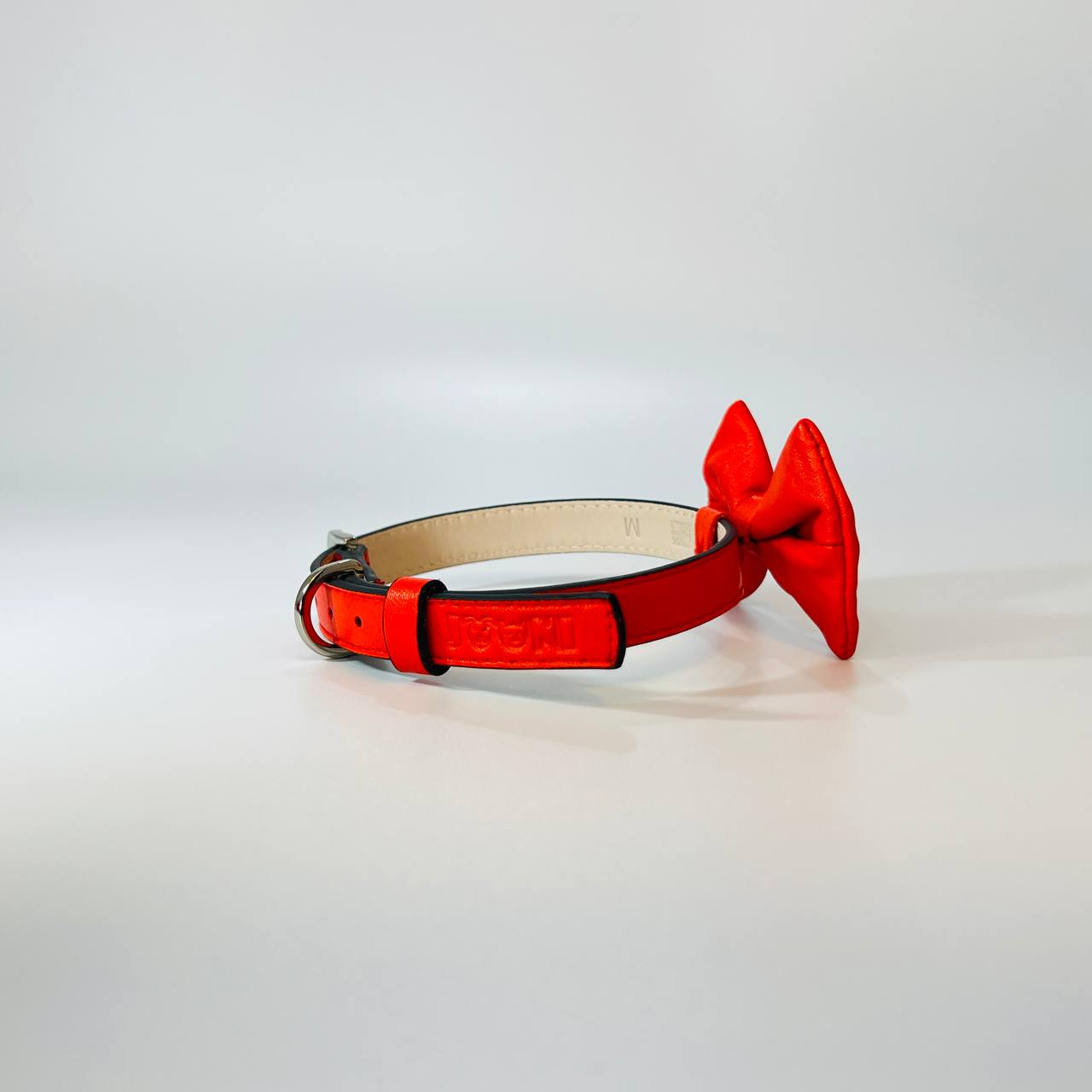 Red dog collar with a bow on a light gray background